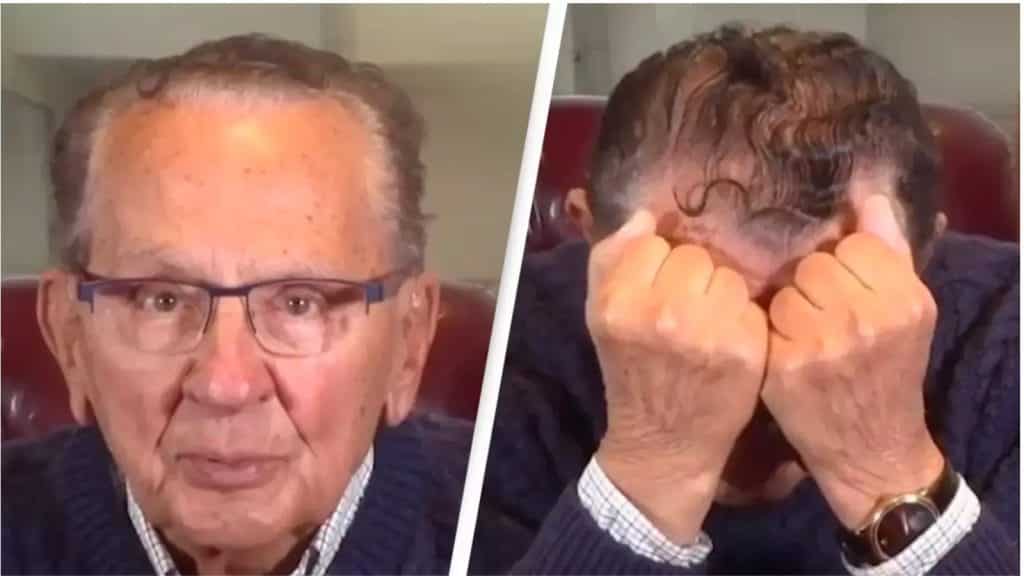 A screenshot from Frank Caprio's video revealing diagnosis. He's wearing a blue sweater with a white collar shirt under it and glasses. Hands on his face.